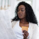 Shocked african american woman reading leaflet before taking contraceptive pills, sitting on couch at home