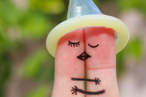 Condom worn on tips of index and middle fingers