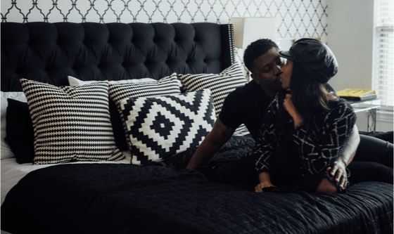 Couple sitting on a bed kissing and cuddling