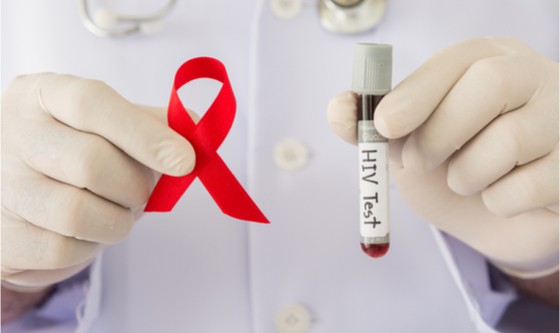 Health care professional holding a test tube and an AIDS ribbon
