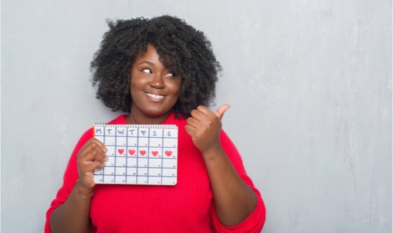 Woman looking happy, holding up a calendar marking her period