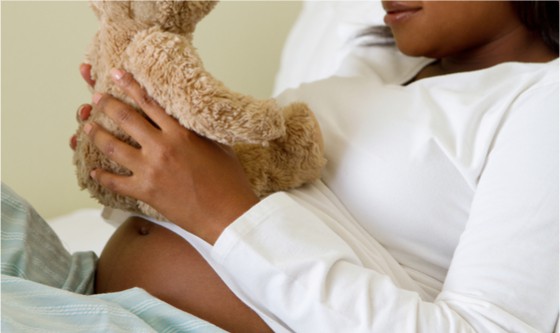 Young pregnant woman holding a teddy bear