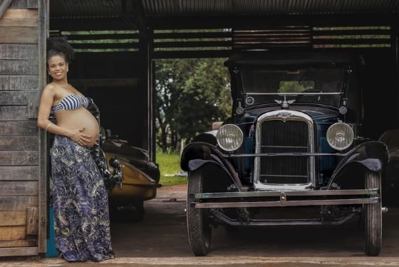 Pregnant women leaning on a wall and holding her bare tummy