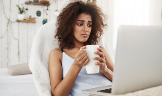 Beautiful young woman looking sad and staring at a computer screen