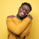 happy man in yellow sweater hugging himself