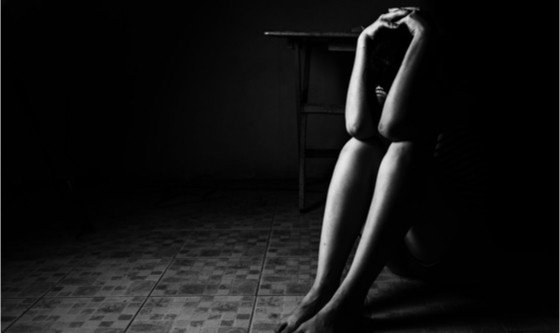 Woman hiding in the corner, covering herself for protection or out of fear
