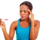 stressed woman staring at a pregnancy test