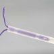 a purple IUD fitted in a clear tube