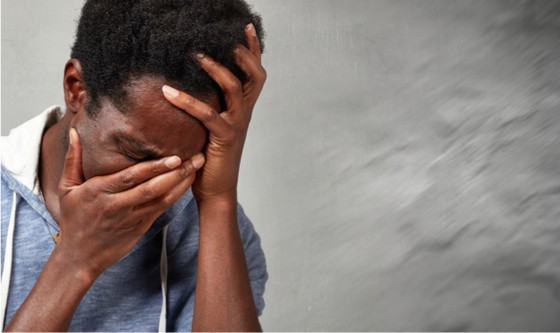 Distressed young man in front of a blurred grey background