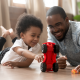 father and son praying with red toy car