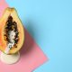 Half of papaya with dripping white liquid on color background