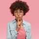 young woman putting her finger over lips to signify keeping quiet