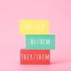 pronouns for different genders hand written on multicolored rectangles against bright pink background